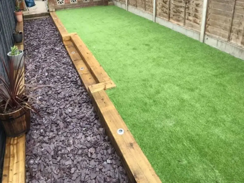 Large garden area with artificial lawn and bordered with sleepers and a small paddling pool
