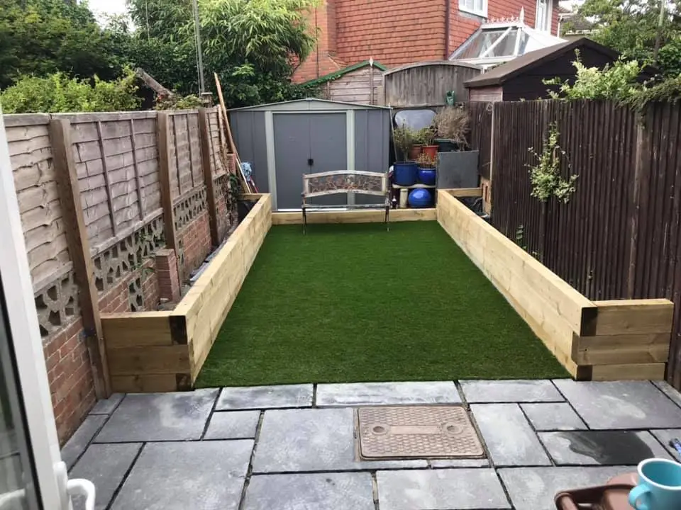 new patio, artificial lawn with sleeper walls for a planting area on either side of the garden
